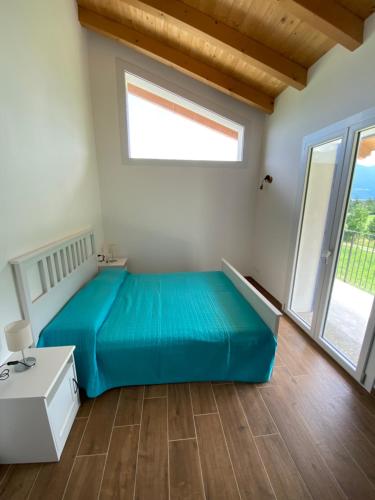 1 dormitorio con 1 cama azul y ventanas grandes en Villa Carlotta Verde en Colico