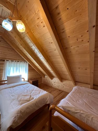 a bedroom with two beds in a wooden cabin at Shtepi Druri Arber in Voskopojë