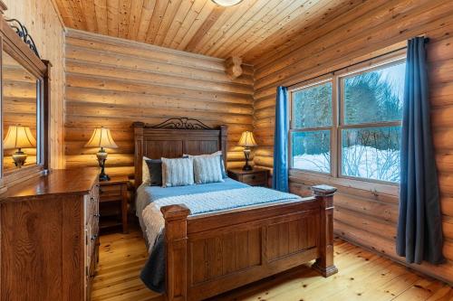 ein Schlafzimmer mit einem Bett in einem Blockhaus in der Unterkunft Fiddler lake Resort Chalet 86 Deer in Mille-Isles