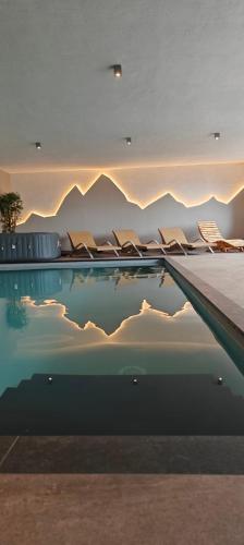 a pool with chairs and mountains in the background at Schlossberg in San Leonardo in Passiria