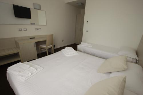 a room with two beds and a desk and a television at Hotel Paradise Airport in Forlì