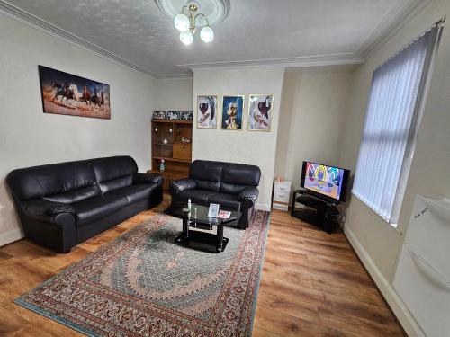 a living room with a leather couch and a television at Homely double bed, TV, Wi-Fi and garden in Leeds