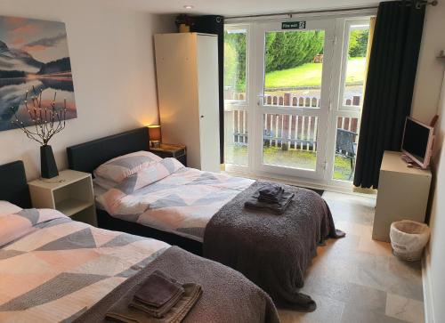 a bedroom with two beds and a window with a balcony at Idyllic 2 Bedroom Self-Contained UpsideDown Annexe in Llandrindod Wells