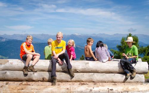 a group of children sitting on top of a log at Schönauerhof in Schlanitzen
