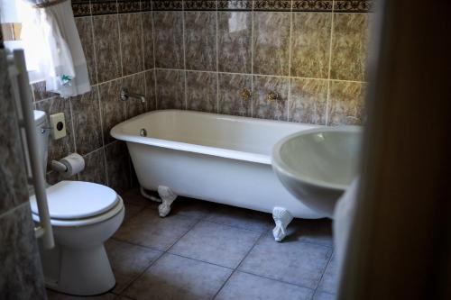 a bathroom with a tub and a toilet and a sink at Altes Landhaus Country Lodge in Oudtshoorn