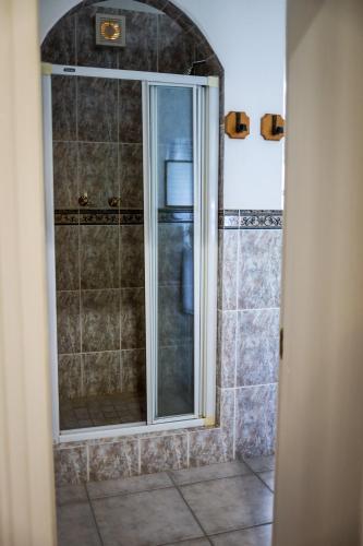 a shower with a glass door in a bathroom at Altes Landhaus Country Lodge in Oudtshoorn