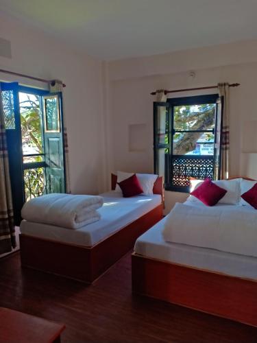 two beds in a room with two windows at Maya Hotel in Bandīpur