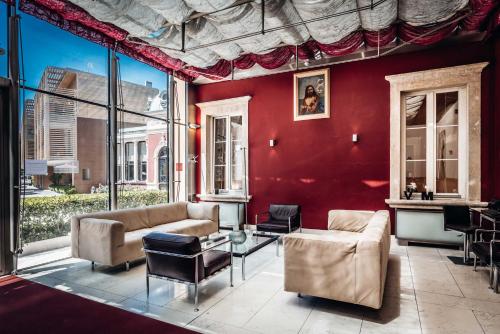 a living room with red walls and a couch and chairs at Hotel Villa Madruzzo in Trento