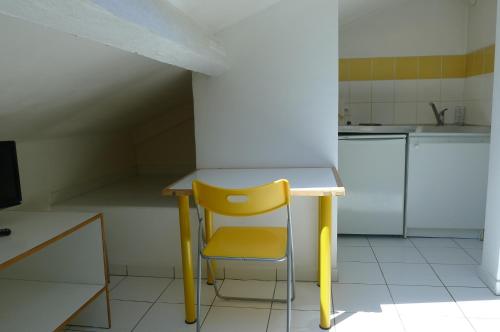 une chaise jaune assise à côté d'une table dans une cuisine dans l'établissement Cannes center apartment, à Cannes