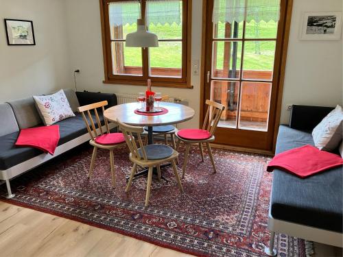 a living room with a table and chairs and a couch at Ferienwohnung Morgentau am Rande der Wildnis in Sibratsgfäll
