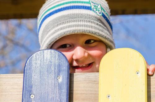 a young boy wearing a hat and smiling with his skateboards at Schönauerhof in Schlanitzen