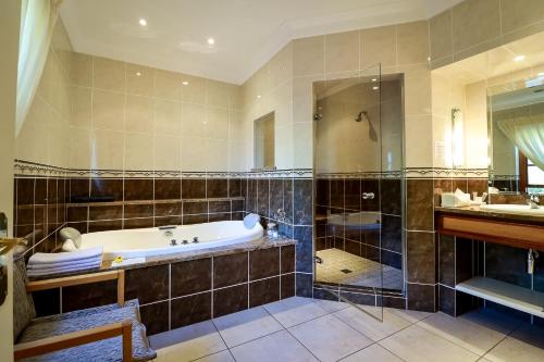 un ampio bagno con vasca e lavandino di Altes Landhaus Country Lodge a Oudtshoorn