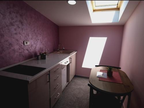 a kitchen with purple walls and a table and a window at Apartmani Maksa in Stanovo