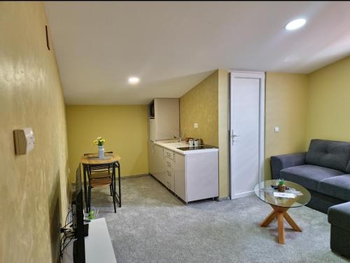 a living room with a blue couch and a kitchen at Apartmani Maksa in Stanovo