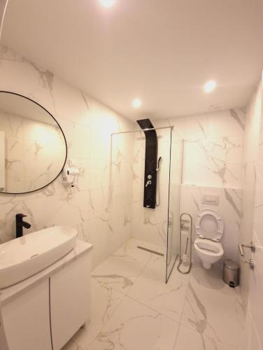 a white bathroom with a toilet and a sink at Apartmani Maksa in Stanovo