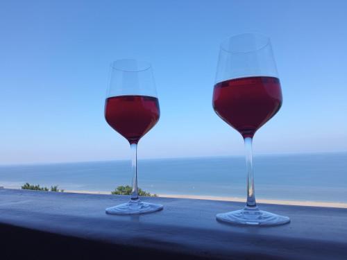 dois copos de vinho tinto sentados numa mesa em Appartement 45m2 - Proche Deauville - Vue Mer em Bénerville-sur-Mer