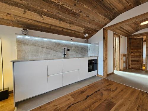 a kitchen with white cabinets and wooden ceilings at Magnifique attique avec vue sur le lac de la Moubra in Crans-Montana