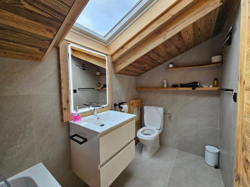 a bathroom with a sink and a toilet with a skylight at Magnifique attique avec vue sur le lac de la Moubra in Crans-Montana