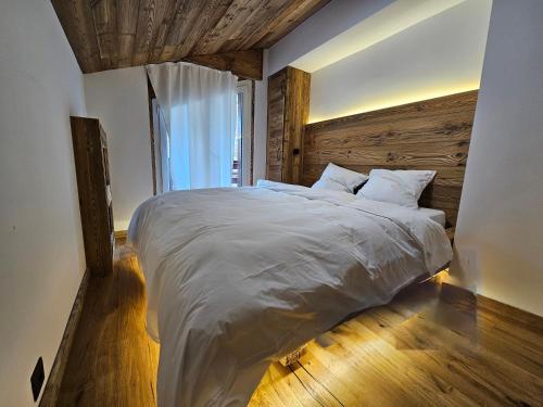 a bedroom with a large bed with a wooden wall at Magnifique attique avec vue sur le lac de la Moubra in Crans-Montana