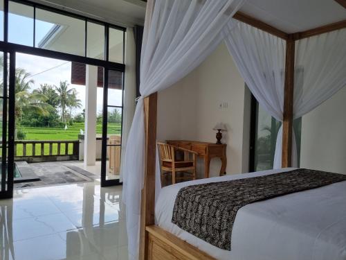 Schlafzimmer mit einem Bett, einem Schreibtisch und einem Fenster in der Unterkunft Villa Padang Santhi in Ubud