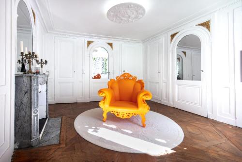 pomarańczowe krzesło w białym pokoju ze stołem w obiekcie Le Boudoir Secret w Besançon