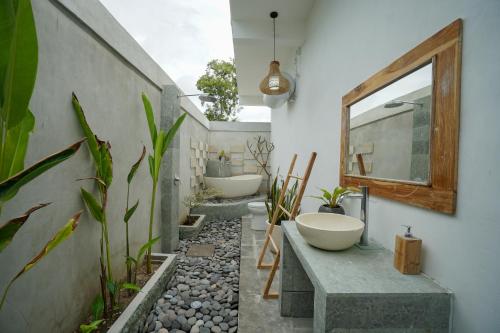a bathroom with two sinks and a mirror and some plants at Innora Jungle Resort And Spa in Nusa Penida