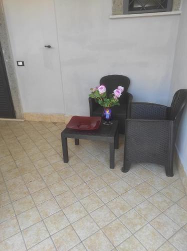 a room with two chairs and a table with a vase of flowers at Dreams House Paola-luxury suite near airport in Fiumicino