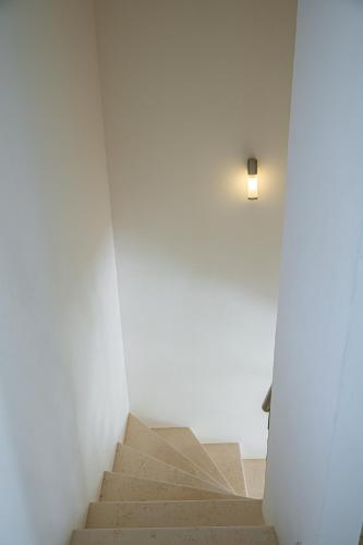 a staircase in a white room with a light on the wall at Costa Bianca Villas in Koilás