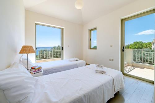 two beds in a room with two large windows at Costa Bianca Villas in Koilás