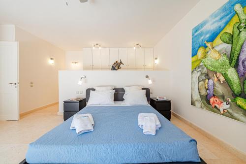 a bedroom with a blue bed and a large painting at Costa Bianca Villas in Koilás