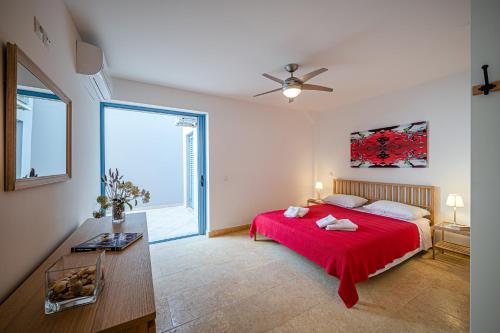 a bedroom with a red bed and a large window at Costa Bianca Villas in Koilás