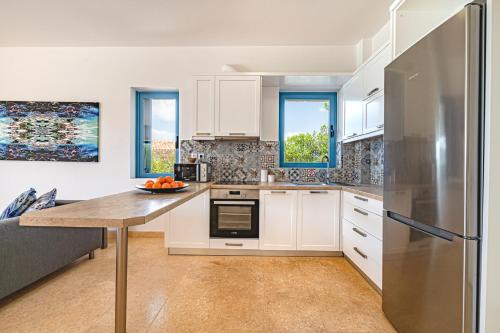 a kitchen with white cabinets and a stainless steel refrigerator at Costa Bianca Villas in Koilás