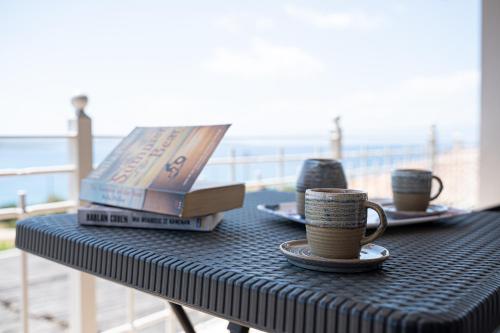 a table with two coffee cups and books on it at Costa Bianca Villas in Koilás