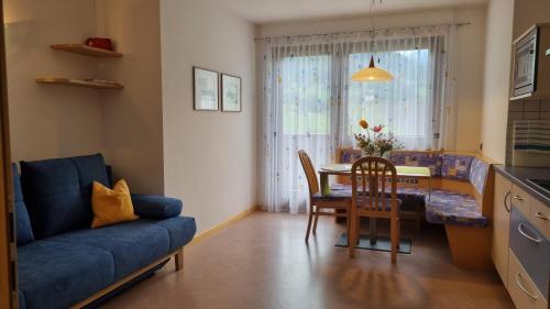 ein Wohnzimmer mit einem blauen Sofa und einem Tisch in der Unterkunft Ferienappartements Eschenleit in St. Pankraz