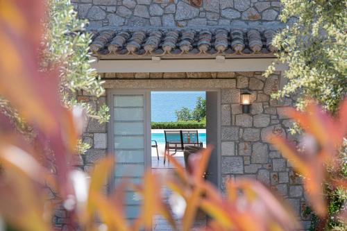 a stone house with a door leading to a pool at Costa Bianca Villas in Koilás