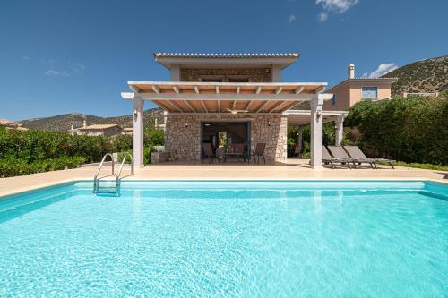 a swimming pool in front of a house with a pergola at Costa Bianca Villas in Koilás