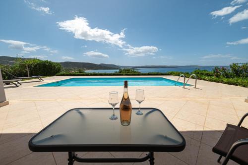 a bottle of wine on a table with two wine glasses at Costa Bianca Villas in Koilás