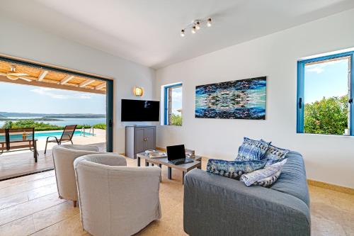 a living room with a couch and chairs and a television at Costa Bianca Villas in Koilás