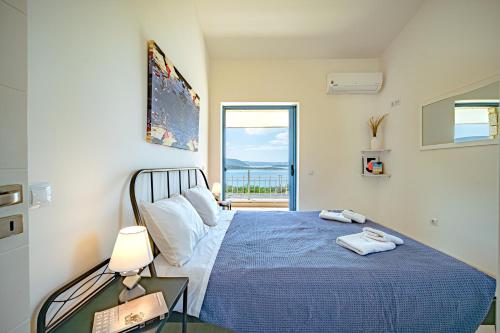 a bedroom with a blue bed with a view of the ocean at Costa Bianca Villas in Koilás