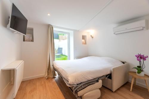 a white bedroom with a bed and a window at Studios Le Médicis in Rouen