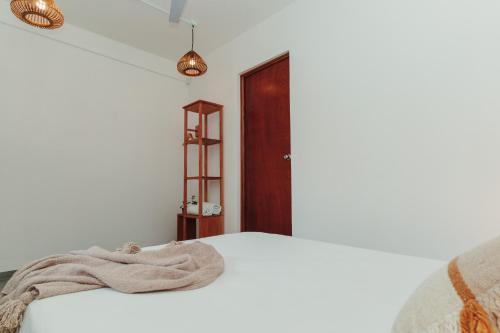 a bedroom with a white bed and a wooden door at Che Zipolite Hostel & Beach Club in Zipolite