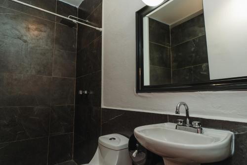 a bathroom with a sink and a mirror and a toilet at Che Zipolite Hostel & Beach Club in Zipolite