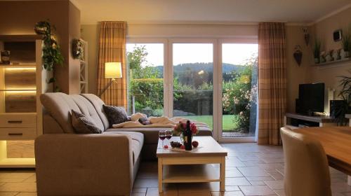 a living room with a couch and a large window at Ferienwohnung Fasse im Solling - Natur hautnah erleben in Uslar
