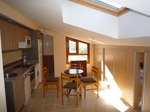 a kitchen with a table and chairs in a room at Apartamentos La Covatilla in Neila de San Miguel