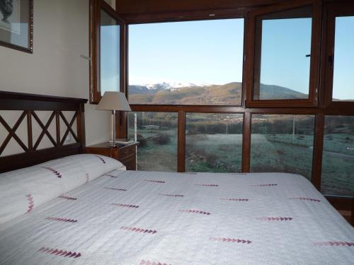 a bedroom with two beds and a large window at Apartamentos La Covatilla in Neila de San Miguel