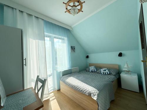 a bedroom with a bed with blue walls and a window at Złote Piaski in Darłowo