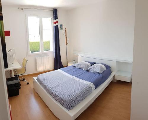 a bedroom with a bed with blue sheets and a window at Le paradis des enfants in La Jarrie