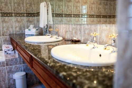 a bathroom with two sinks and a granite counter top at Altes Landhaus Country Lodge in Oudtshoorn