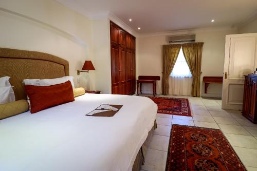 a bedroom with a large white bed in a room at Altes Landhaus Country Lodge in Oudtshoorn