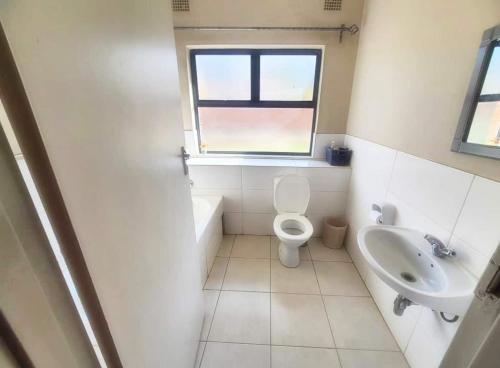 ein Bad mit einem WC, einem Waschbecken und einem Fenster in der Unterkunft Remarkable 2-Bed Apartment in Harare in Harare